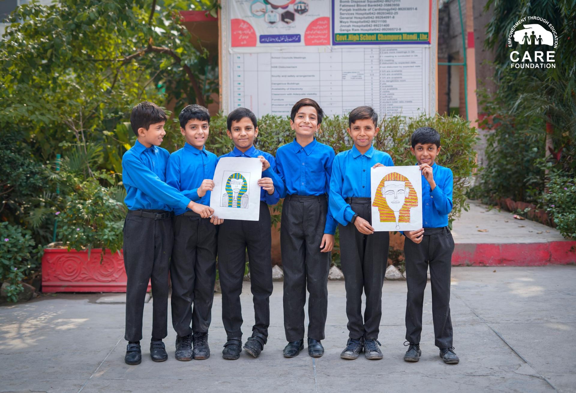 six school children boys holding up drawings